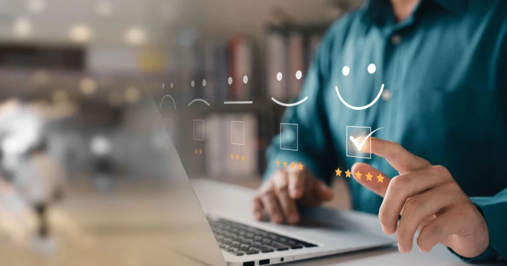 Una persona utiliza un ordenador portátil e interactúa con una pantalla virtual que muestra tres caras sonrientes y casillas de verificación. La carita feliz está marcada y resaltada con cinco estrellas doradas, lo que refleja una atención al cliente inmediata y una experiencia altamente positiva.